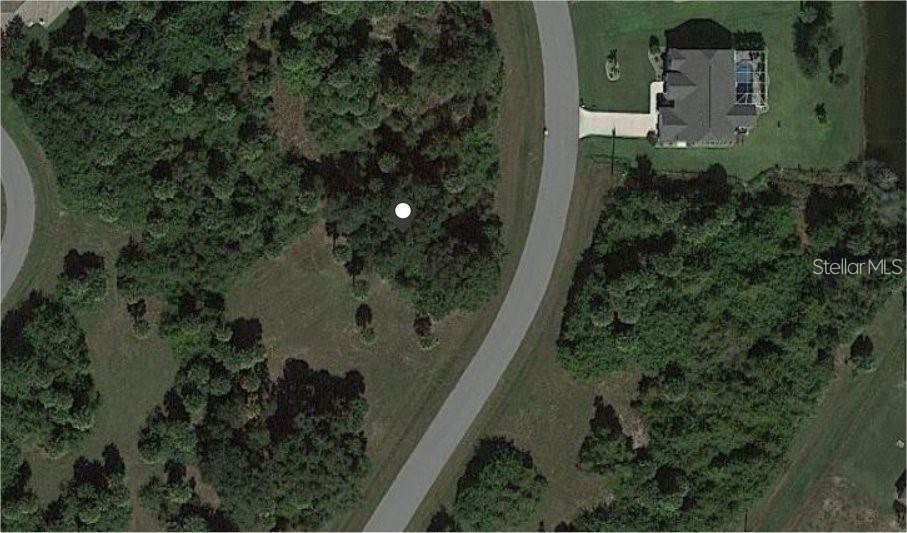An aerial view shows a vacant, wooded residential lot next to a paved road and house — 224 SUNSET ROAD, ROTONDA WEST, FL
