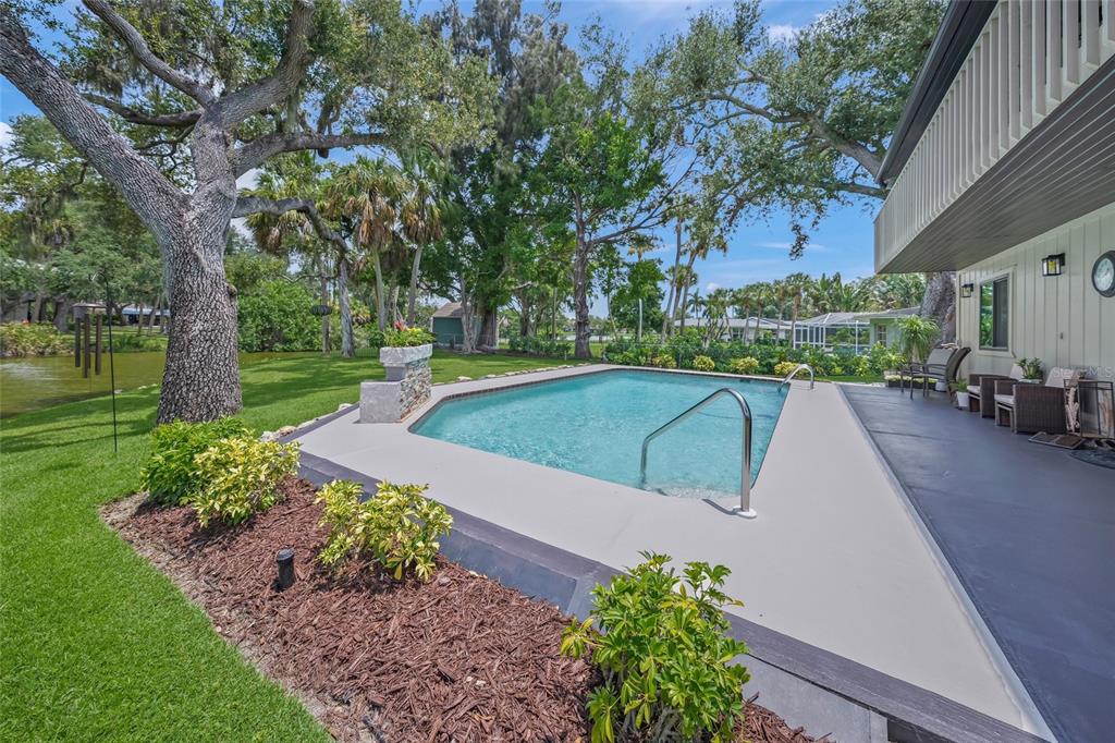 A backyard swimming pool with a concrete deck sits next to a house and lawn — 3643 MERIDALE ROAD, SARASOTA, FL