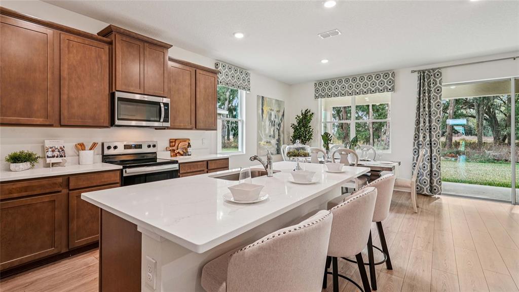 A kitchen features dark wood cabinets, a white quartz island, and a sliding glass door — 4555 NW 39TH STREET ROAD, OCALA, FL