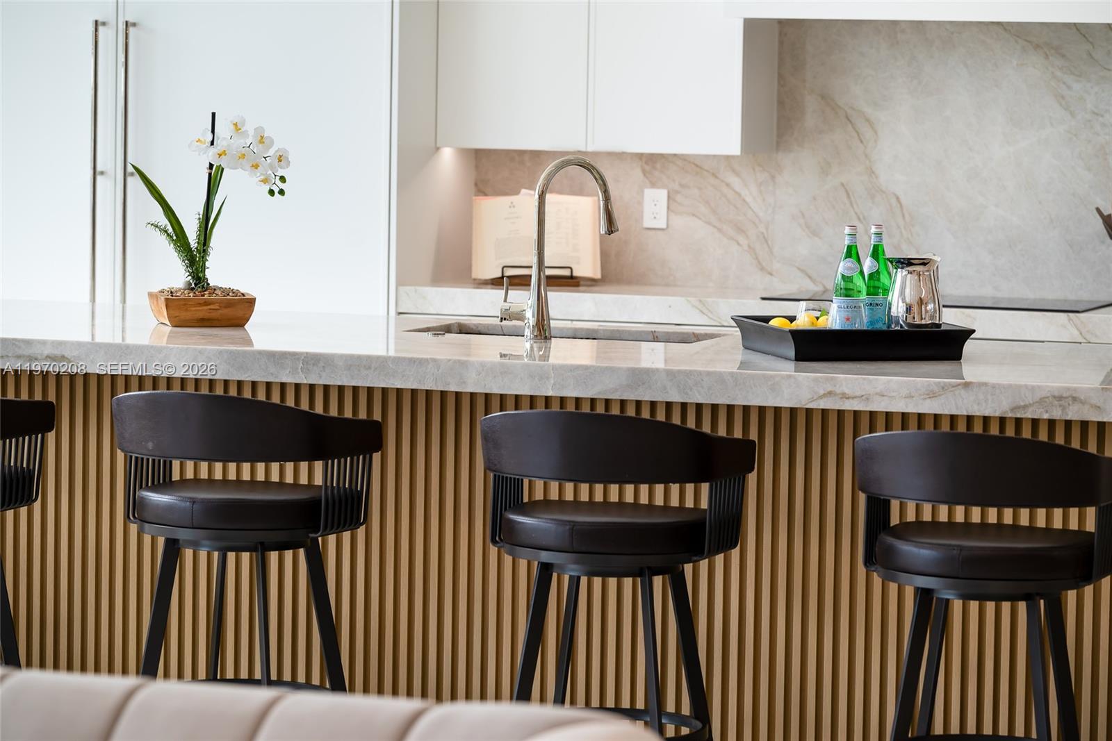 A modern kitchen island features a marble countertop, slatted wood base, and three dark stools — 3740 NE 29th Ave, Lighthouse Point FL 33064, LIGHTHOUSE POINT, FL