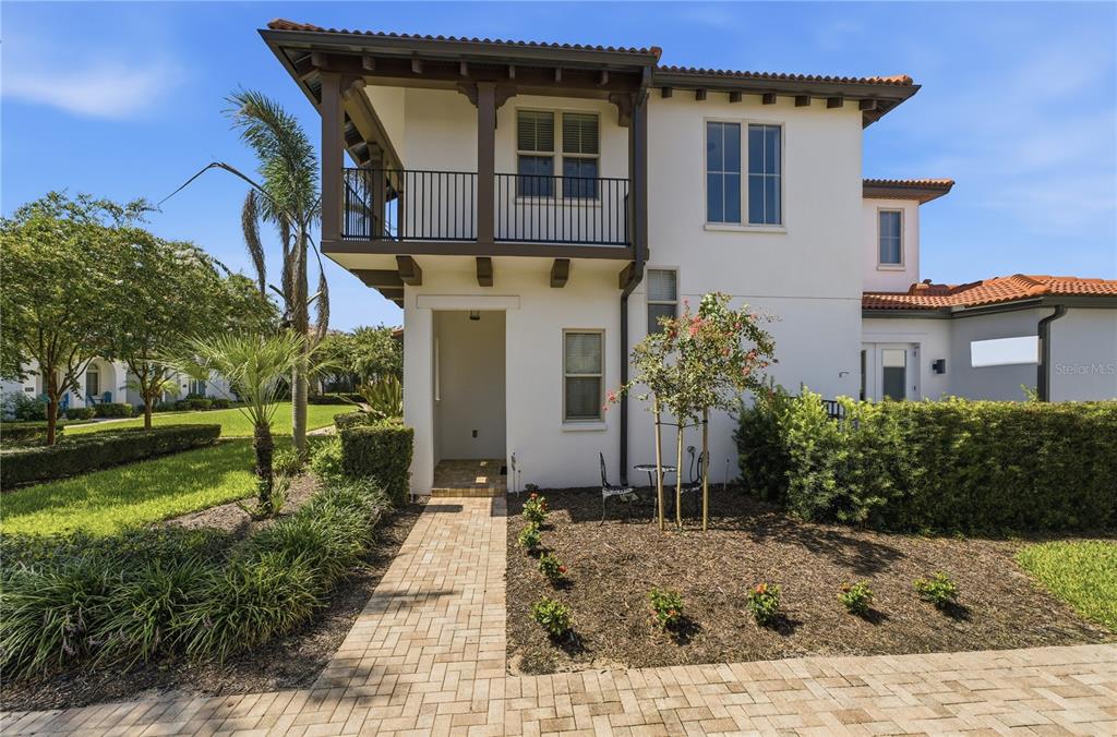 A two-story stucco house with a tiled roof, a second-floor balcony, and a brick walkway — 8873 FOUNTAIN PALM ALLEY, WINTER GARDEN, FL