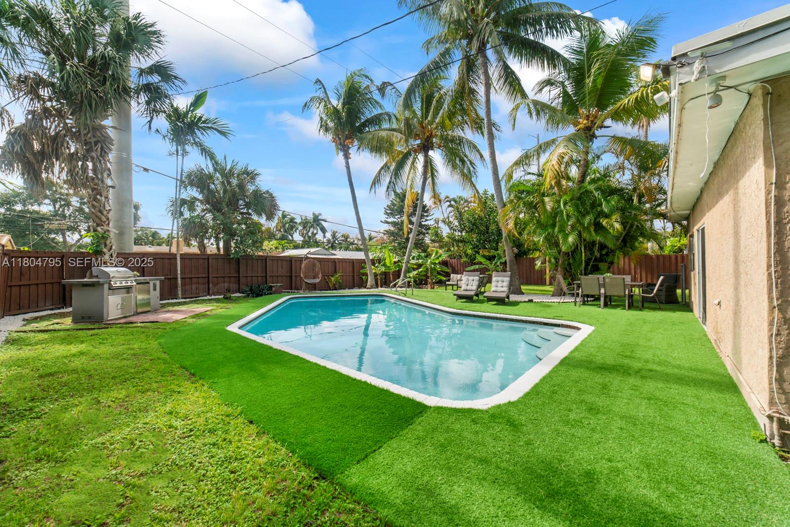 A backyard features a swimming pool, artificial turf, palm trees, and a patio dining area — 2708 Cleveland St, Hollywood FL 33020, HOLLYWOOD, FL