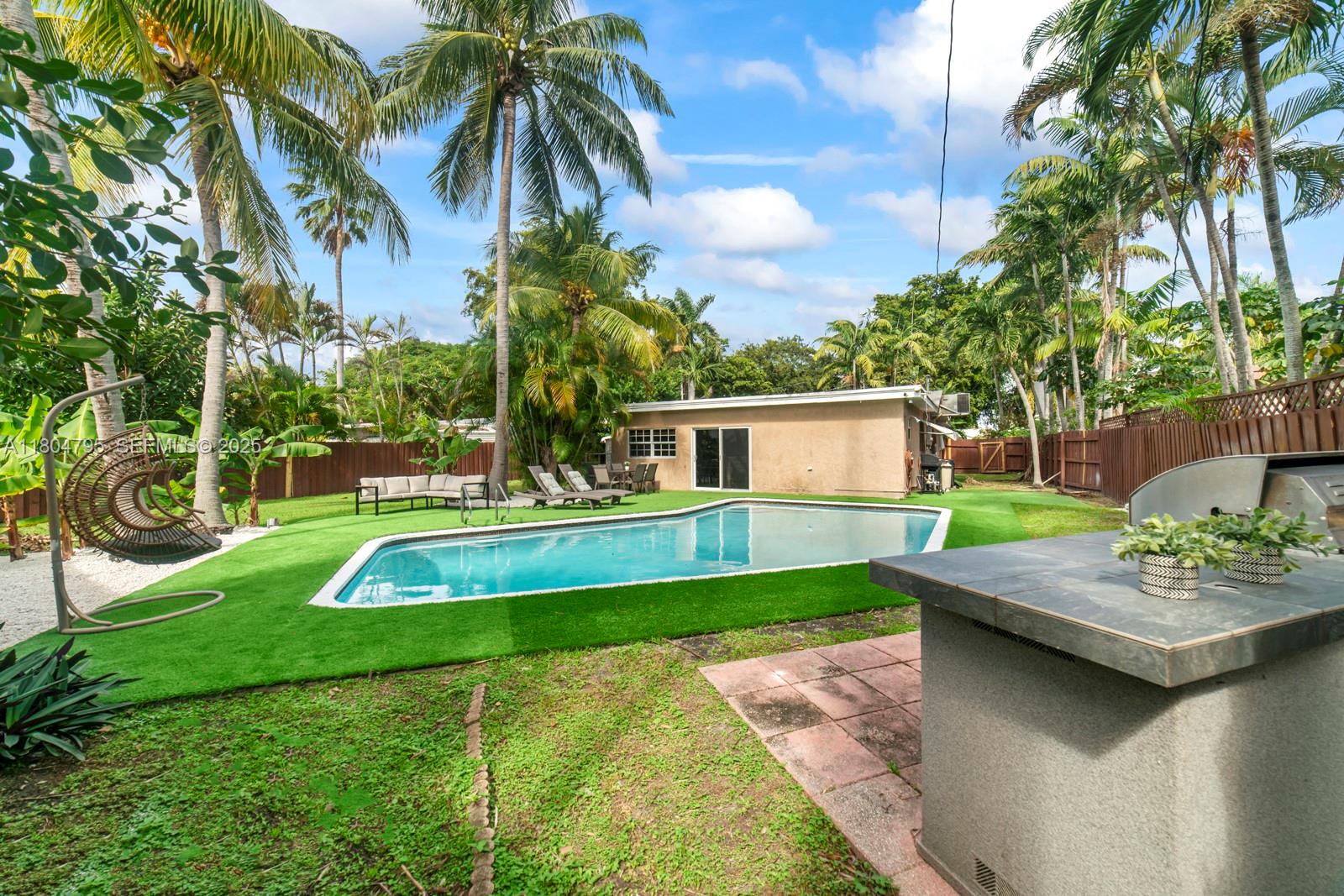 A backyard features a swimming pool, artificial turf, palm trees, and an outdoor grill area — 2708 Cleveland St, Hollywood FL 33020, HOLLYWOOD, FL