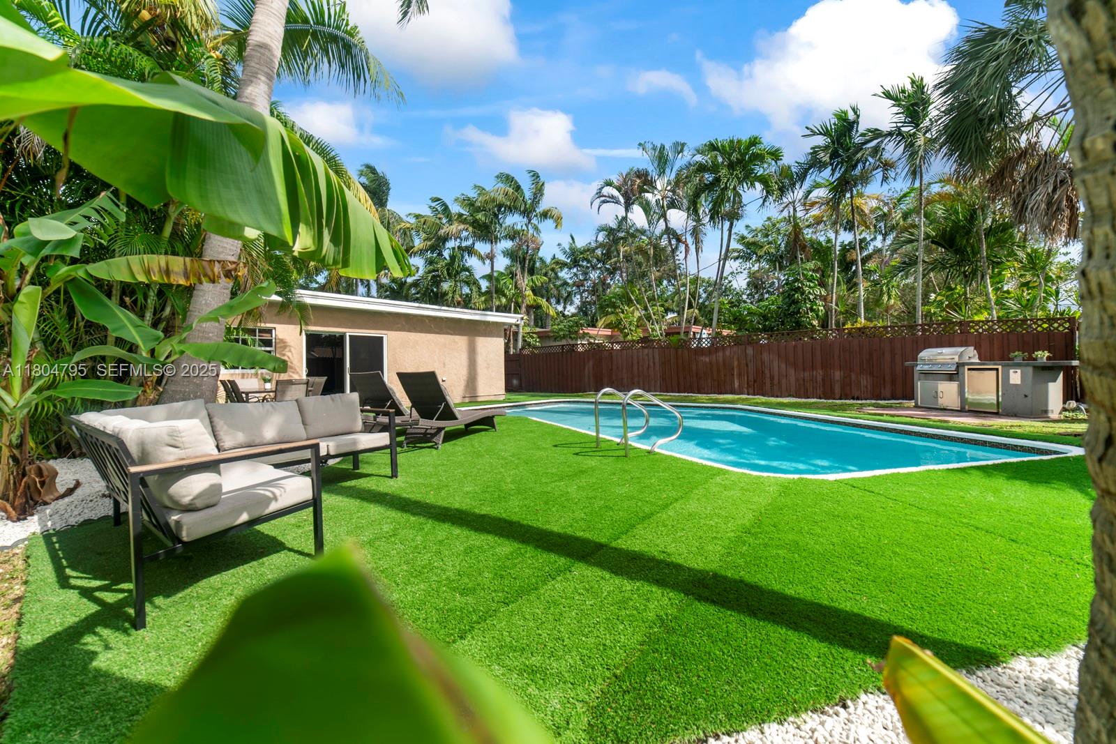 A backyard features a swimming pool, artificial turf, lounge seating, and a grill area — 2708 Cleveland St, Hollywood FL 33020, HOLLYWOOD, FL