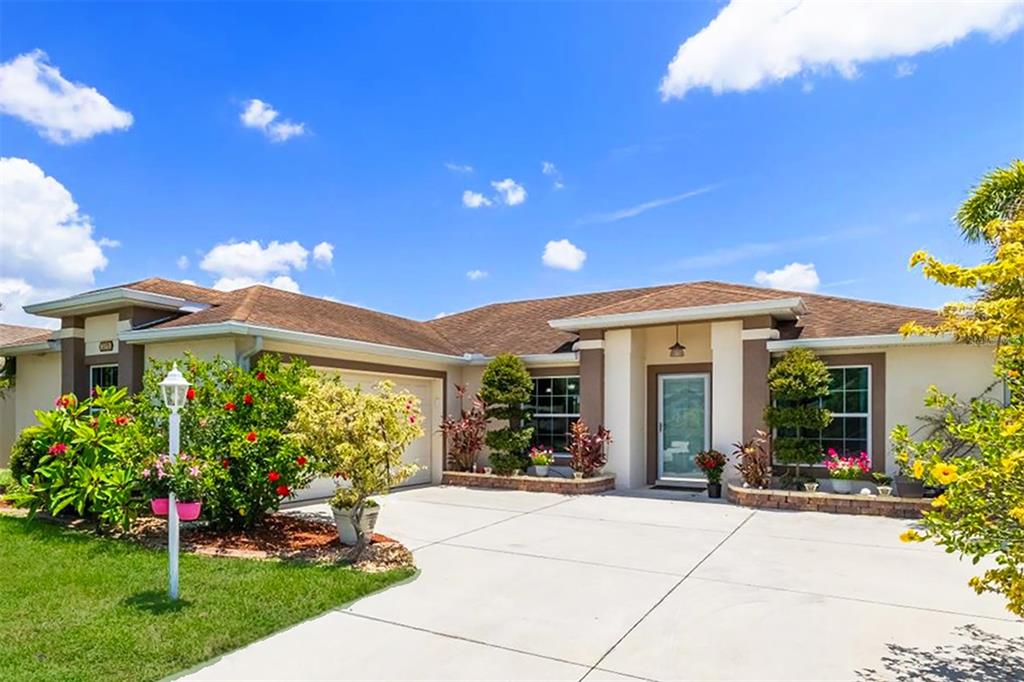A single-story house with a concrete driveway, tan stucco walls, and a brown shingled roof — 3215 55TH STREET E, PALMETTO, FL