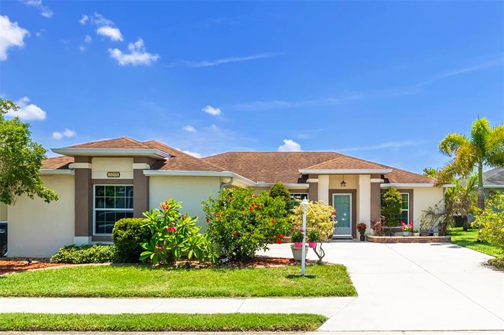 A single-story house with a brown roof, beige stucco walls, and a concrete driveway — 3215 55TH STREET E, PALMETTO, FL