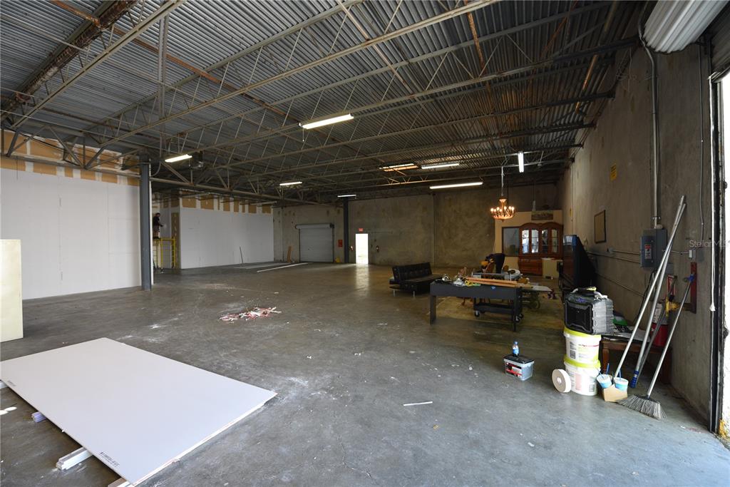 An open-concept industrial warehouse space features exposed metal ceiling trusses, concrete floors, and drywall partitions — 1211 TECH BOULEVARD UNIT 169, TAMPA, FL