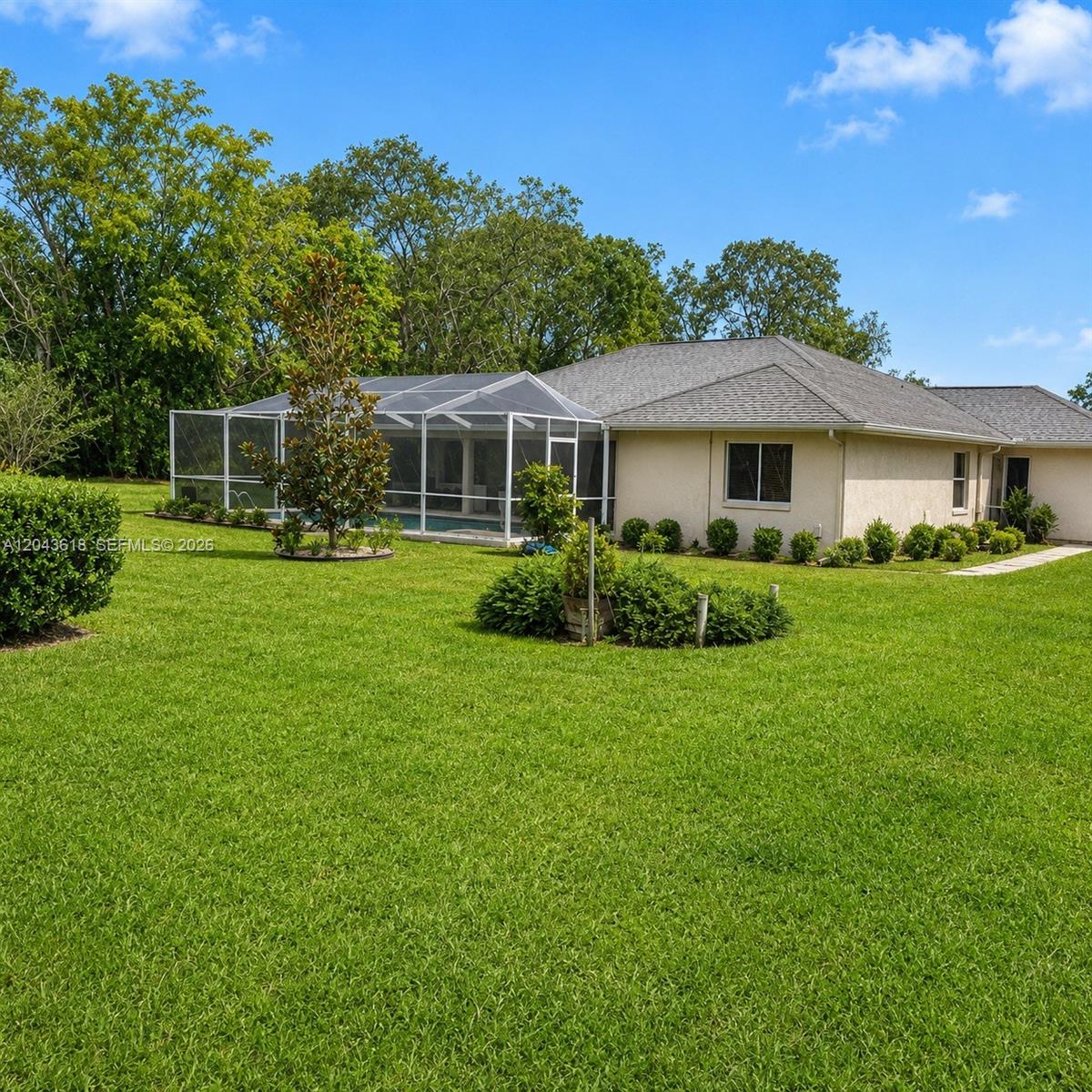 A backyard features a house with a screened-in pool enclosure and a large grassy lawn — 16321 S Fiscus, Spring Hill FL 34610, SPRING HILL, FL