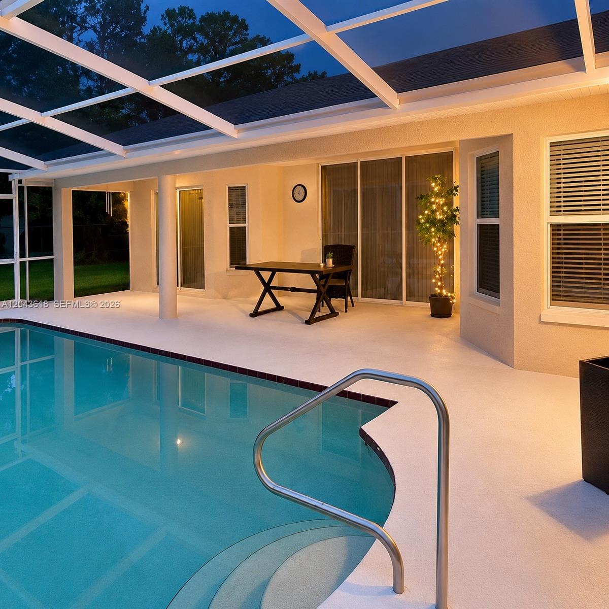 A covered patio features a swimming pool, a dining table, and a lighted potted tree — 16321 S Fiscus, Spring Hill FL 34610, SPRING HILL, FL