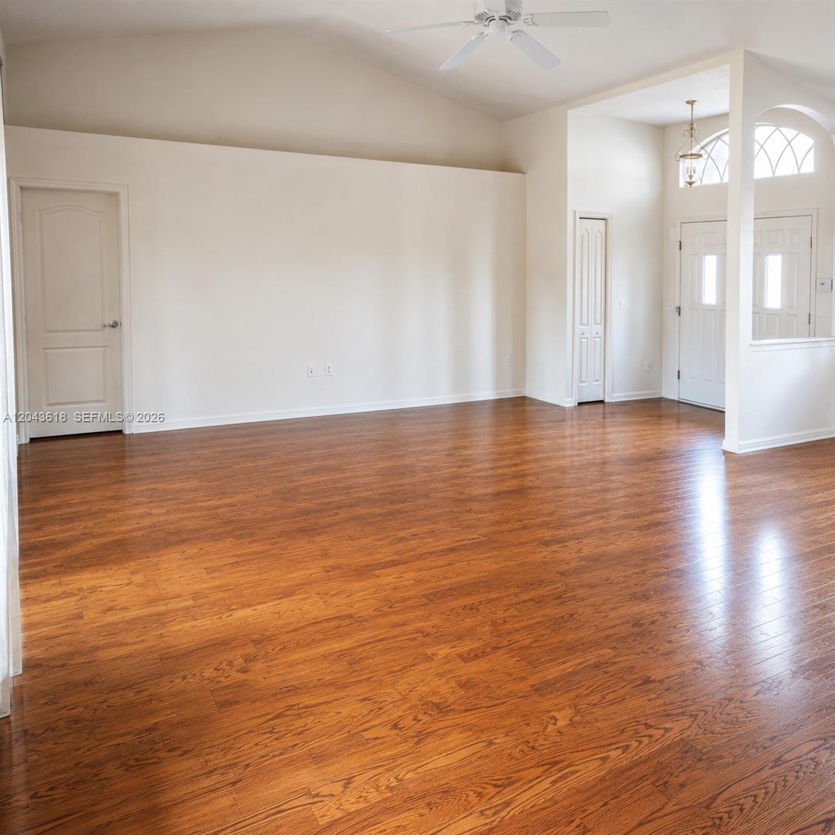 An empty living room features vaulted ceilings, hardwood floors, and an entryway with arched windows — 16321 S Fiscus, Spring Hill FL 34610, SPRING HILL, FL