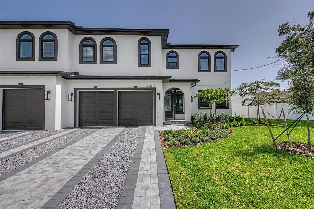 A two-story white townhouse with dark-framed arched windows and a paved driveway — 110 S ARRAWANA AVENUE UNIT 2, TAMPA, FL