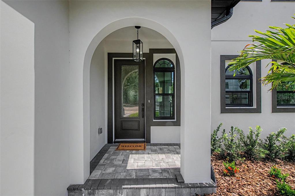 A covered entryway features a dark-framed glass door, an arched opening, and stone paver flooring — 110 S ARRAWANA AVENUE UNIT 2, TAMPA, FL