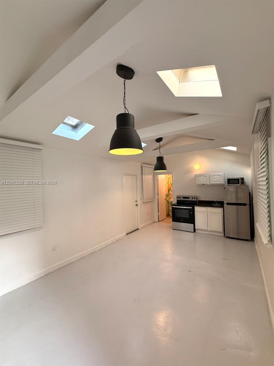 A kitchen and living area features white walls, concrete floors, skylights, and pendant lighting — 118 NW 24th St, Miami FL 33127, MIAMI, FL