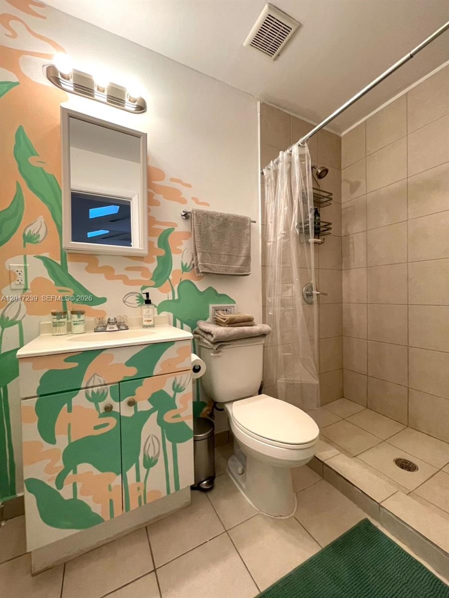A bathroom features a floral-painted vanity, a toilet, and a tiled walk-in shower — 118 NW 24th St, Miami FL 33127, MIAMI, FL