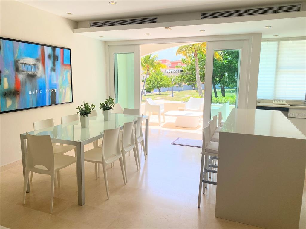 A dining room with a glass table, white chairs, and sliding doors leading to a patio — 14 PENINSULA  DE SAN JUAN STREET, HUMACAO, PR