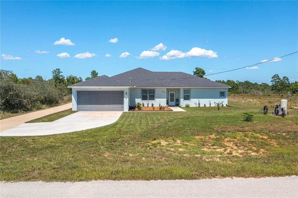 A single-story house with a gray roof, light-colored siding, and an attached two-car garage — 182 WOODSTORK WAY, FROSTPROOF, FL