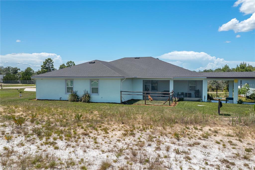 The rear exterior of a single-story house features a screened-in porch and a fenced yard — 182 WOODSTORK WAY, FROSTPROOF, FL