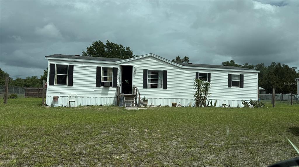 A single-story white mobile home with black shutters sits on a grassy lot — 6289 SE 140TH PLACE, SUMMERFIELD, FL