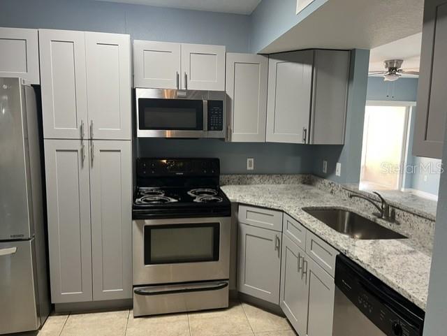 A kitchen features light gray cabinets, stainless steel appliances, and speckled granite countertops — 495 LAS CORTES LANE UNIT 102, ORLANDO, FL