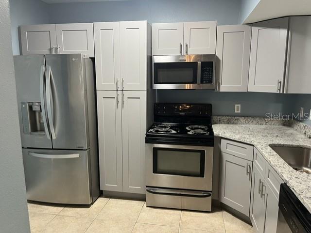 A kitchen features light gray cabinets, stainless steel appliances, and speckled granite countertops — 495 LAS CORTES LANE UNIT 102, ORLANDO, FL