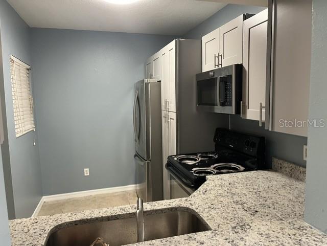 A kitchen features white cabinets, stainless steel appliances, and granite countertops — 495 LAS CORTES LANE UNIT 102, ORLANDO, FL