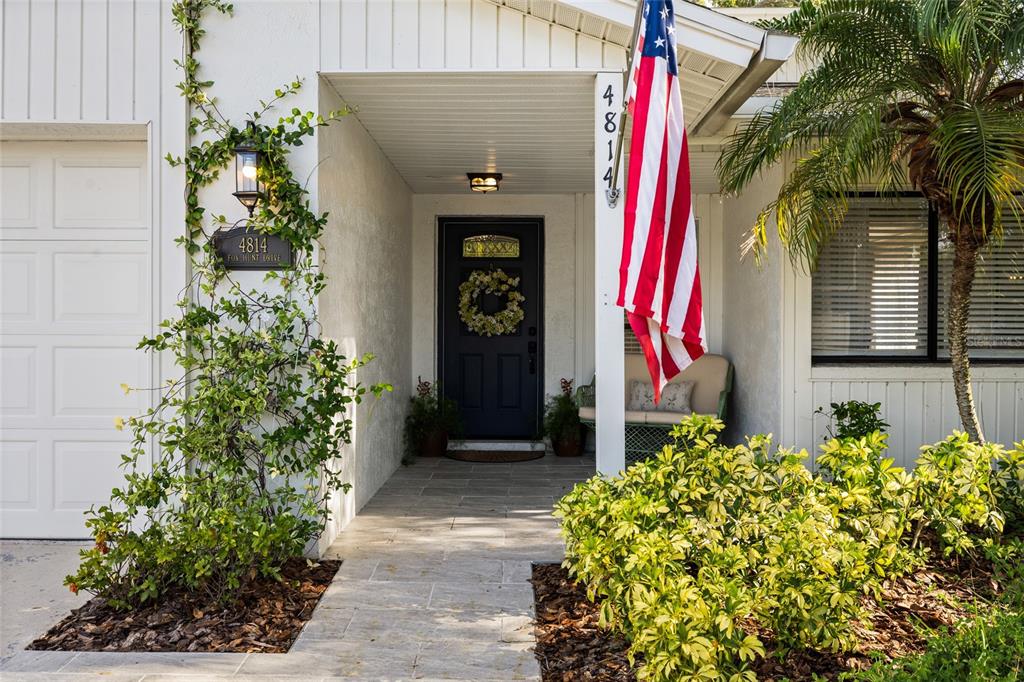 The front exterior of a house features a dark door, a flag, and landscaping — 4814 FOX HUNT DR, TAMPA, FL