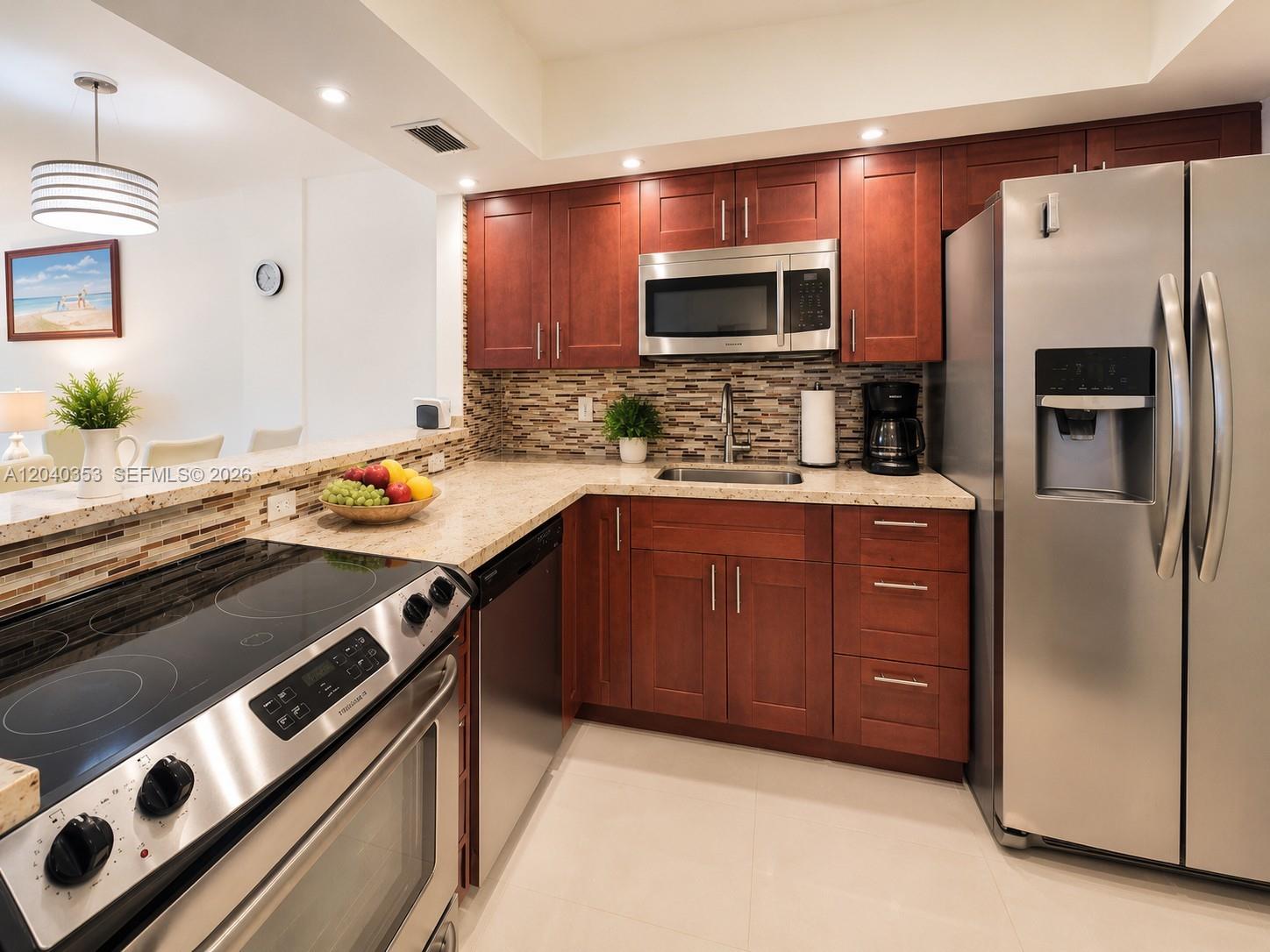 A kitchen features cherry wood cabinets, stainless steel appliances, and a granite countertop — 1333 E Hallandale Beach Blvd # 106, Hallandale Beach FL 33009, HALLANDALE BEACH, FL