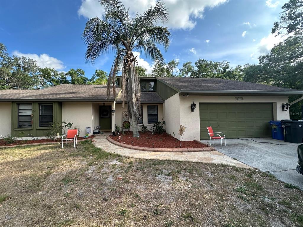 A single-story house with a palm tree, a two-car garage, and a stone walkway — 3104 BROKEN ARROW COURT, WIMAUMA, FL