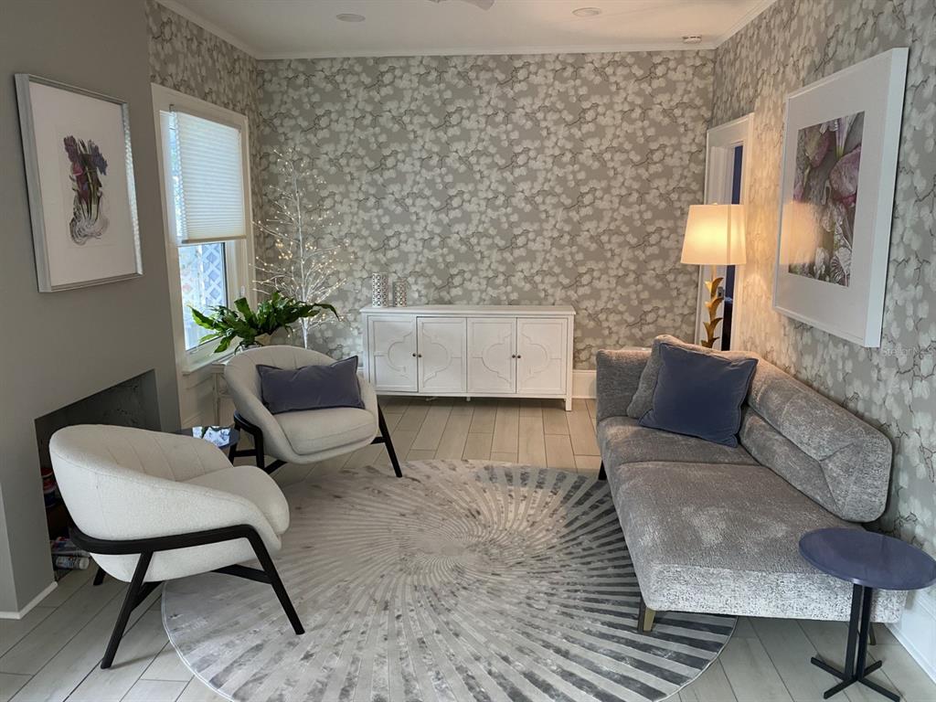 A living room features patterned wallpaper, a gray sofa, two white armchairs, and a rug — 5416 4TH AVENUE W, BRADENTON, FL