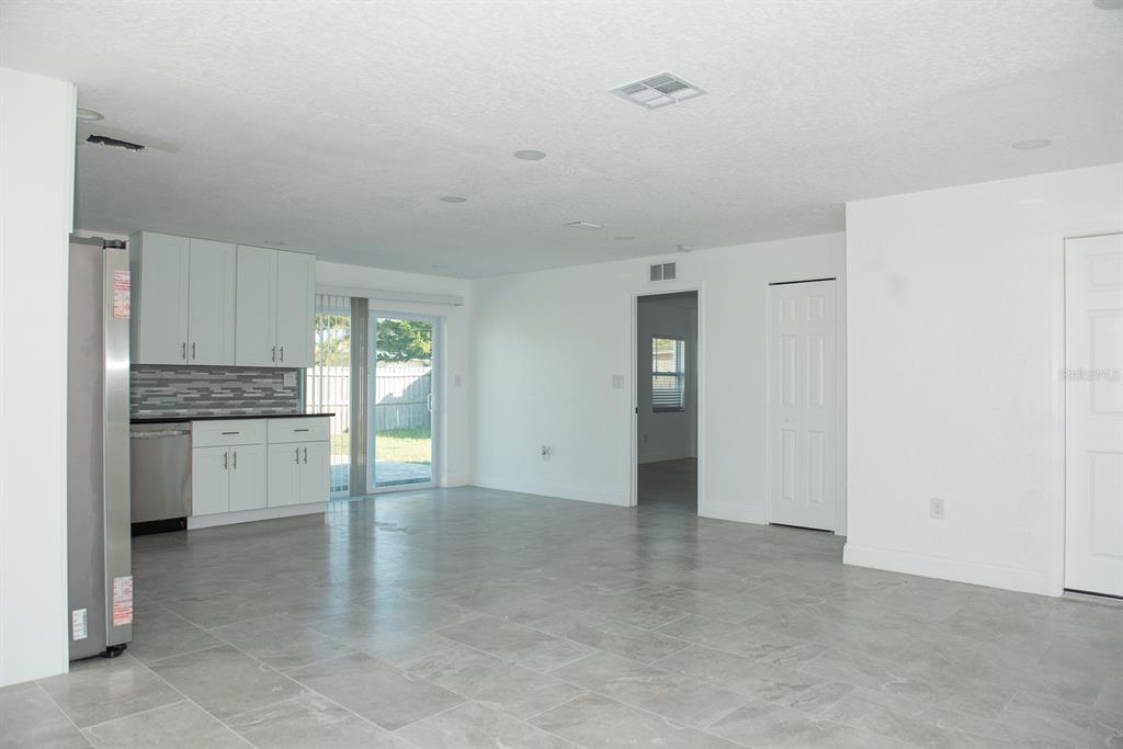 A kitchen with white cabinets and gray tile flooring opens to a sliding glass door — 11889 93RD AVENUE, SEMINOLE, FL