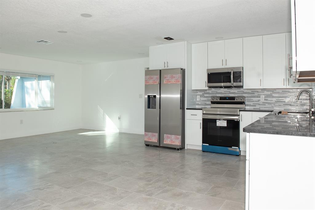 A kitchen with white cabinets, stainless steel appliances, and gray tile flooring — 11889 93RD AVENUE, SEMINOLE, FL