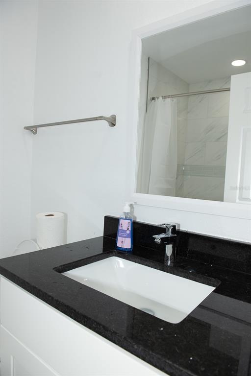 A bathroom features a white vanity with a black countertop, a sink, and a mirror — 11889 93RD AVENUE, SEMINOLE, FL