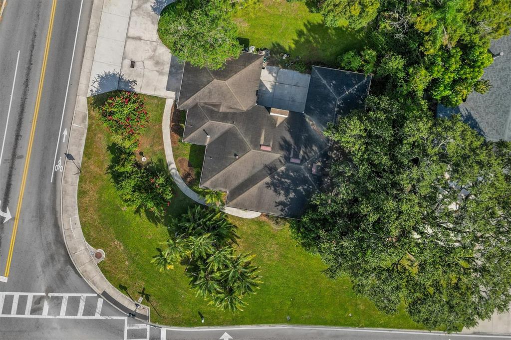An aerial view shows a house with a dark roof surrounded by trees and grass — 225 LAKE HOLLINGSWORTH DRIVE, LAKELAND, FL