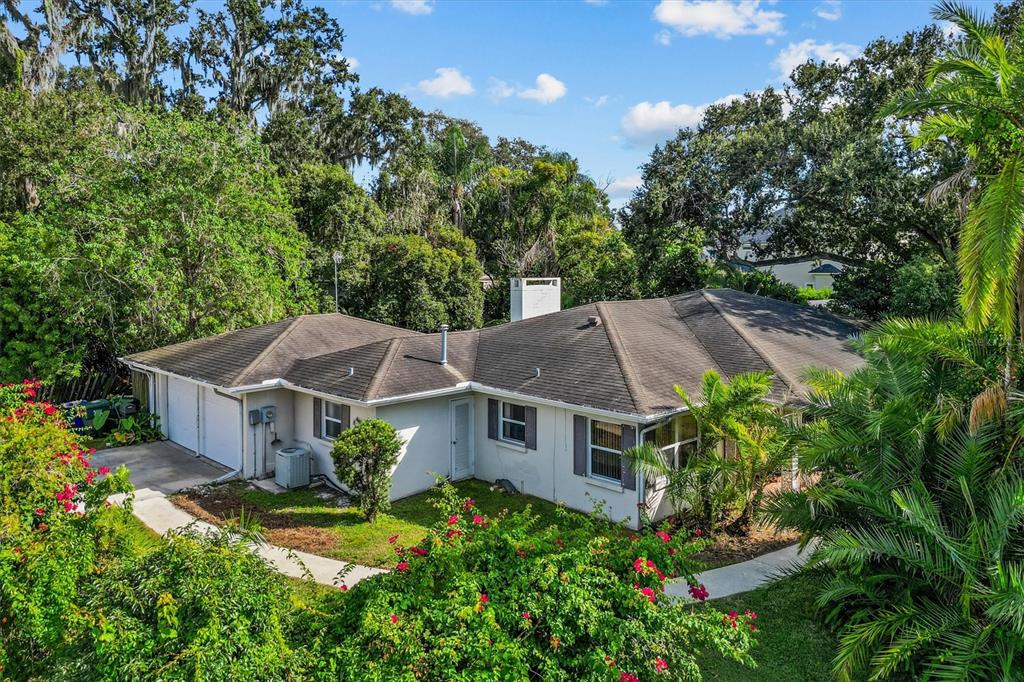 An exterior view of a single-story house with a white facade and a dark roof — 225 LAKE HOLLINGSWORTH DRIVE, LAKELAND, FL