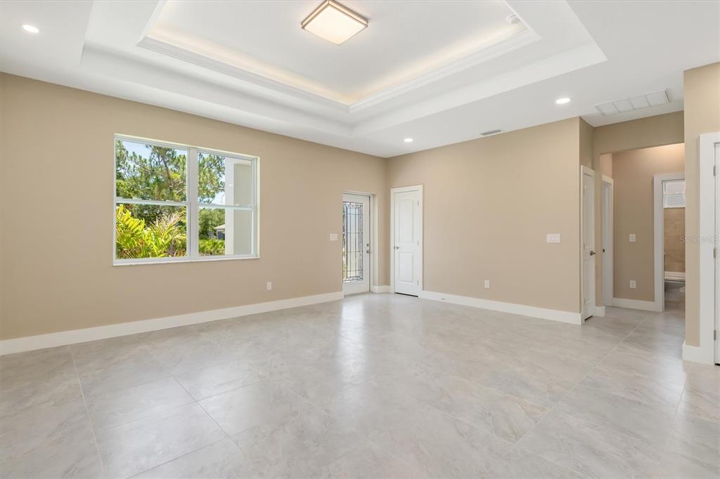 An empty room with beige walls, tile flooring, a tray ceiling, and a glass-paneled door — 5265 CAPUTO AVENUE, NORTH PORT, FL
