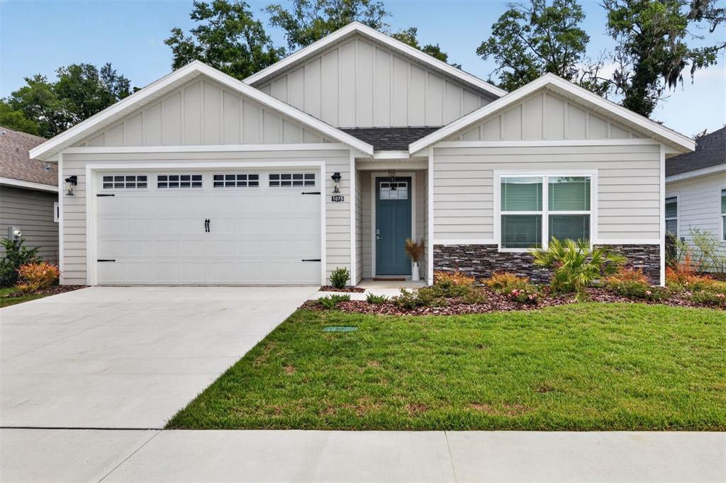 A single-story house with light gray siding, a two-car garage, and a blue front door — 1075 SW 66TH TERRACE, GAINESVILLE, FL