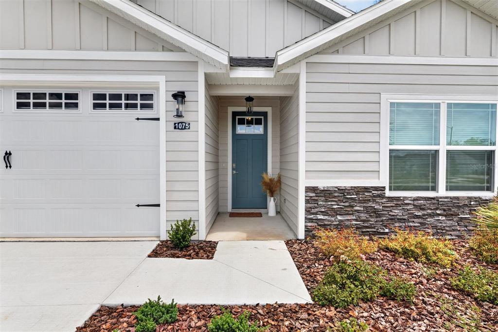 The exterior of a house features a blue front door, garage, and stone veneer siding — 1075 SW 66TH TERRACE, GAINESVILLE, FL