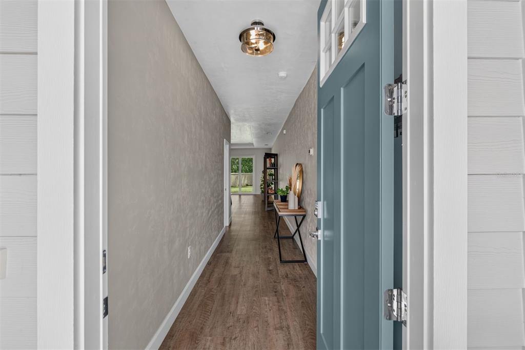 A view from an open blue door into a hallway with wood-look flooring — 1075 SW 66TH TERRACE, GAINESVILLE, FL