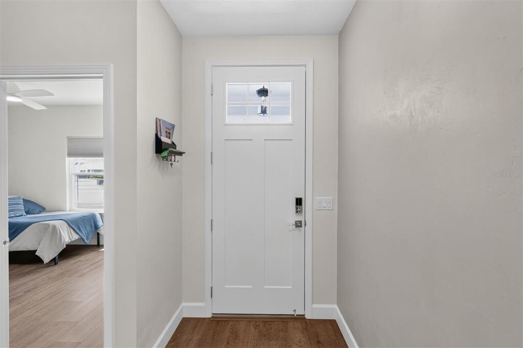 A white front door with a glass pane opens into a foyer with wood flooring — 1075 SW 66TH TERRACE, GAINESVILLE, FL