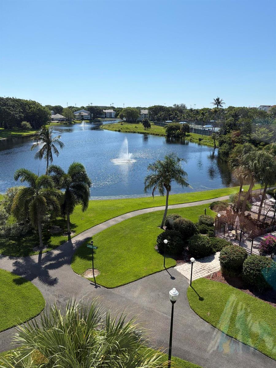 An elevated view of a lake with fountains, palm trees, and a paved walking path — 1915 Lavers Circle # E508, Delray Beach FL 33444, DELRAY BEACH, FL