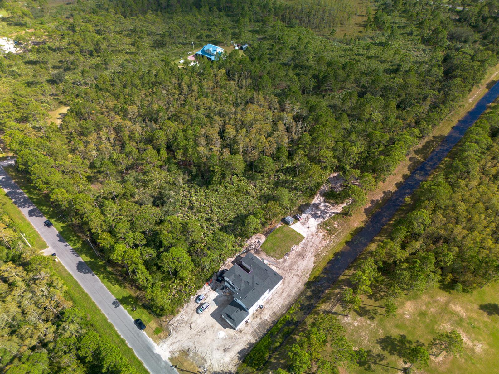 An aerial view shows a house under construction on a wooded lot beside a canal — 0 Sabal Street, Orlando FL 32833, ORLANDO, FL