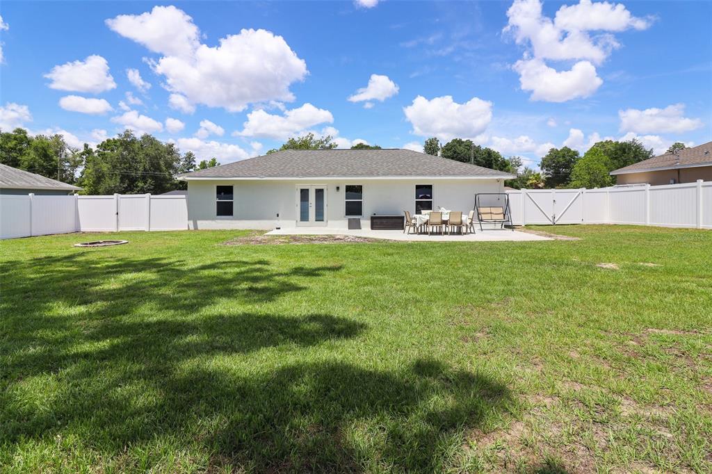 The backyard features a white house with a patio, outdoor furniture, and a vinyl fence — 12193 SE 87TH TERRACE, BELLEVIEW, FL