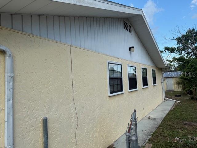 The side exterior of a yellow stucco house features a white gable and three windows — 499 WATER ROAD, OCALA, FL