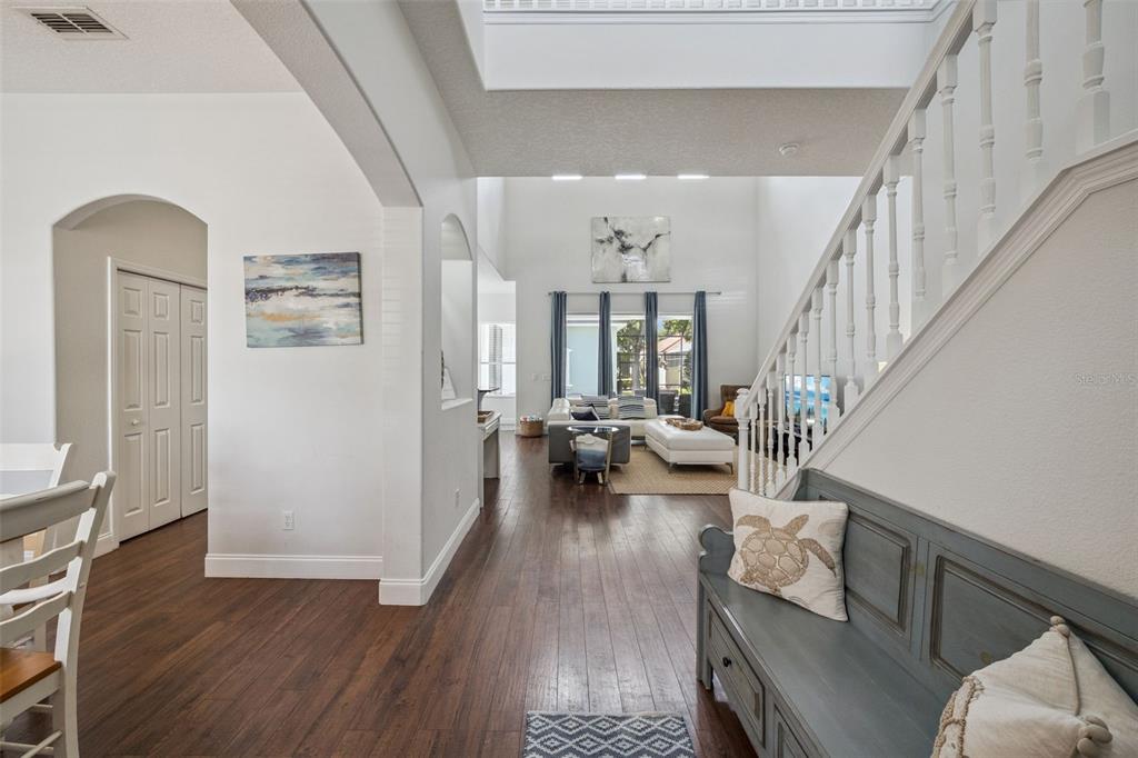 A view from an entryway looking into a living room with hardwood floors and stairs — 7412 DEVEREAUX STREET, KISSIMMEE, FL