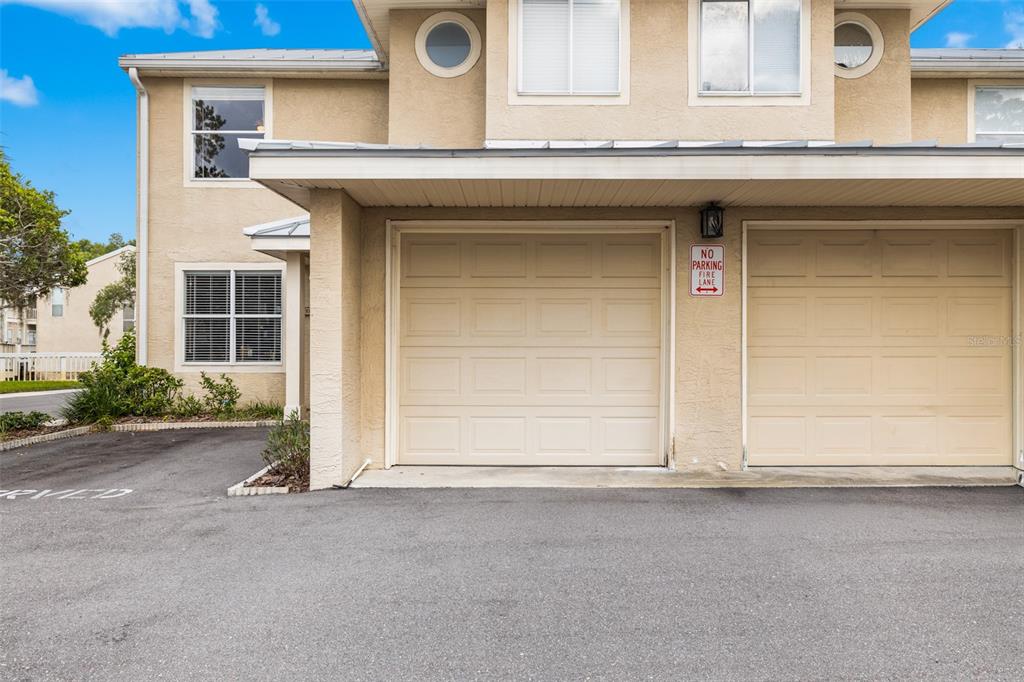 A two-story tan stucco building features a two-car garage with a no parking sign — 13007 LORNA PLACE, TAMPA, FL
