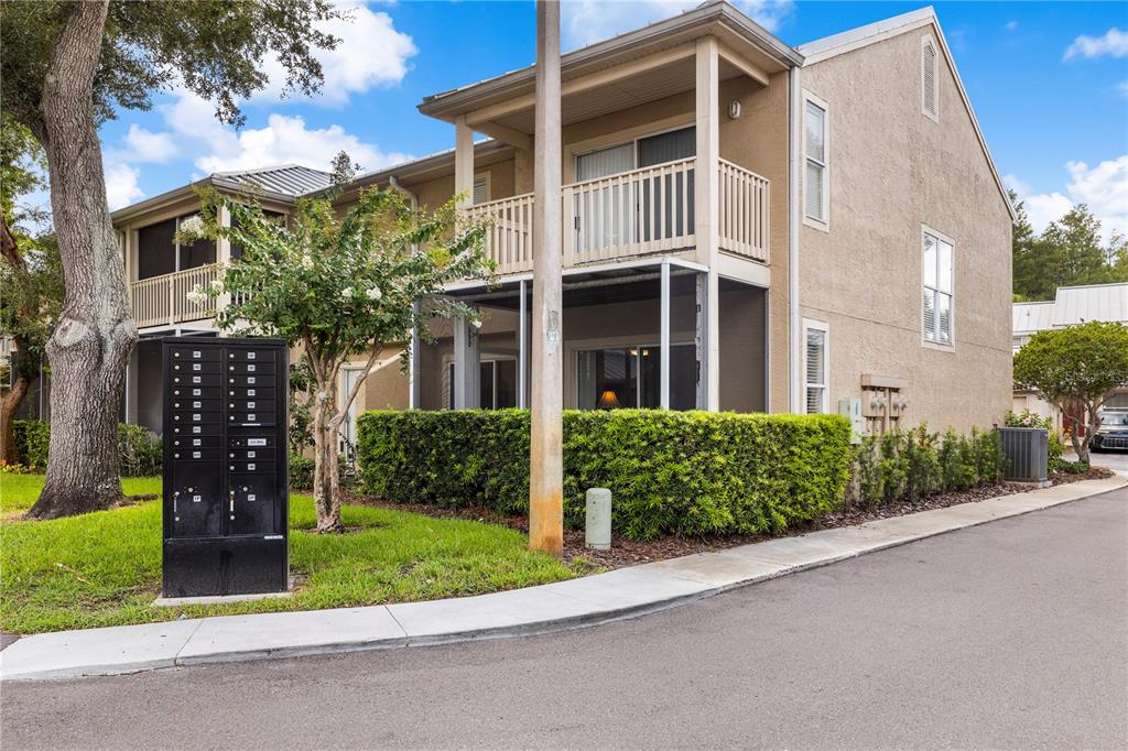 A two-story tan stucco townhouse with a screened-in patio, balcony, and a communal mailbox unit — 13007 LORNA PLACE, TAMPA, FL