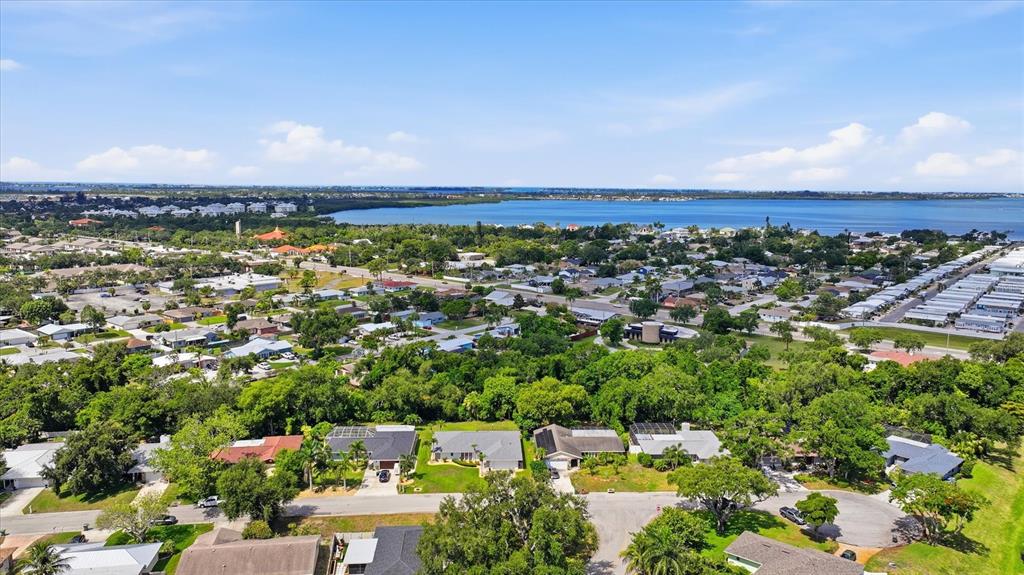An aerial view shows a suburban neighborhood with houses, trees, and a large body of water — 2130 72ND STREET CIRCLE W, BRADENTON, FL