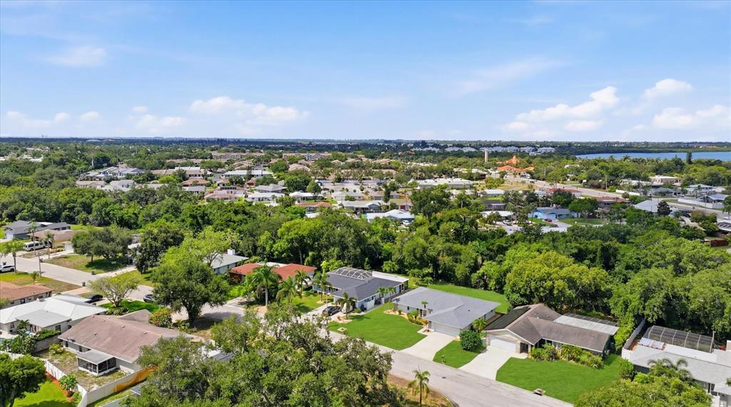 An aerial view shows a suburban neighborhood with single-family homes, lush trees, and paved streets — 2130 72ND STREET CIRCLE W, BRADENTON, FL