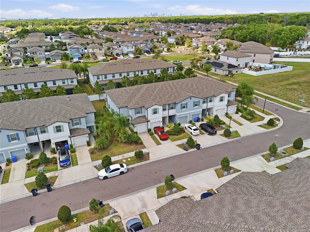 An aerial view shows a suburban neighborhood with multi-family townhomes, paved streets, and parked cars — 4540 GLOBE THISTLE DRIVE, TAMPA, FL
