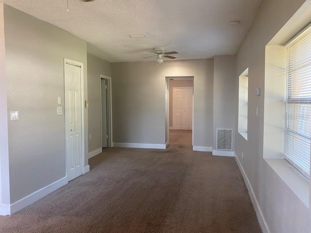 An empty room with beige carpet, light-colored walls, a ceiling fan, and a window — 741 W OSCEOLA STREET, CLERMONT, FL